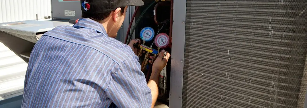 HVAC technician servicing a condenser unit in Pontiac