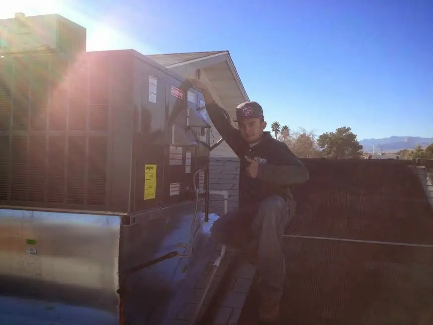 HVAC technician performing AC Tune-Up on a rooftop unit in Pontiac